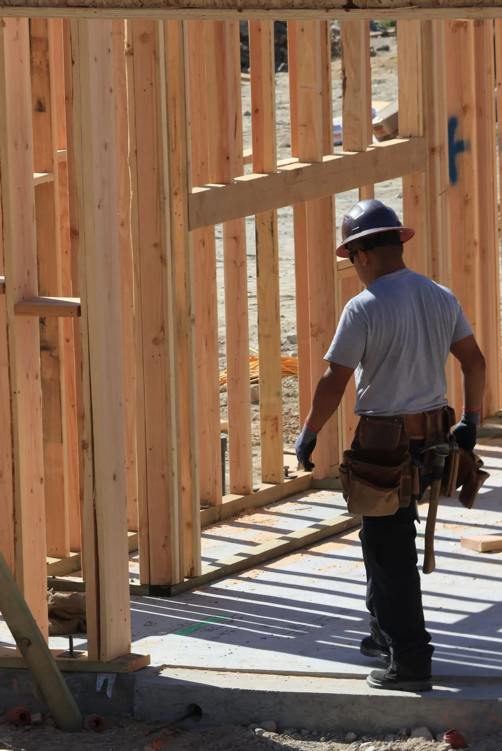 Contractor in a hard hat framing a wooden house. Contractor marketing for estimates and true emergencies