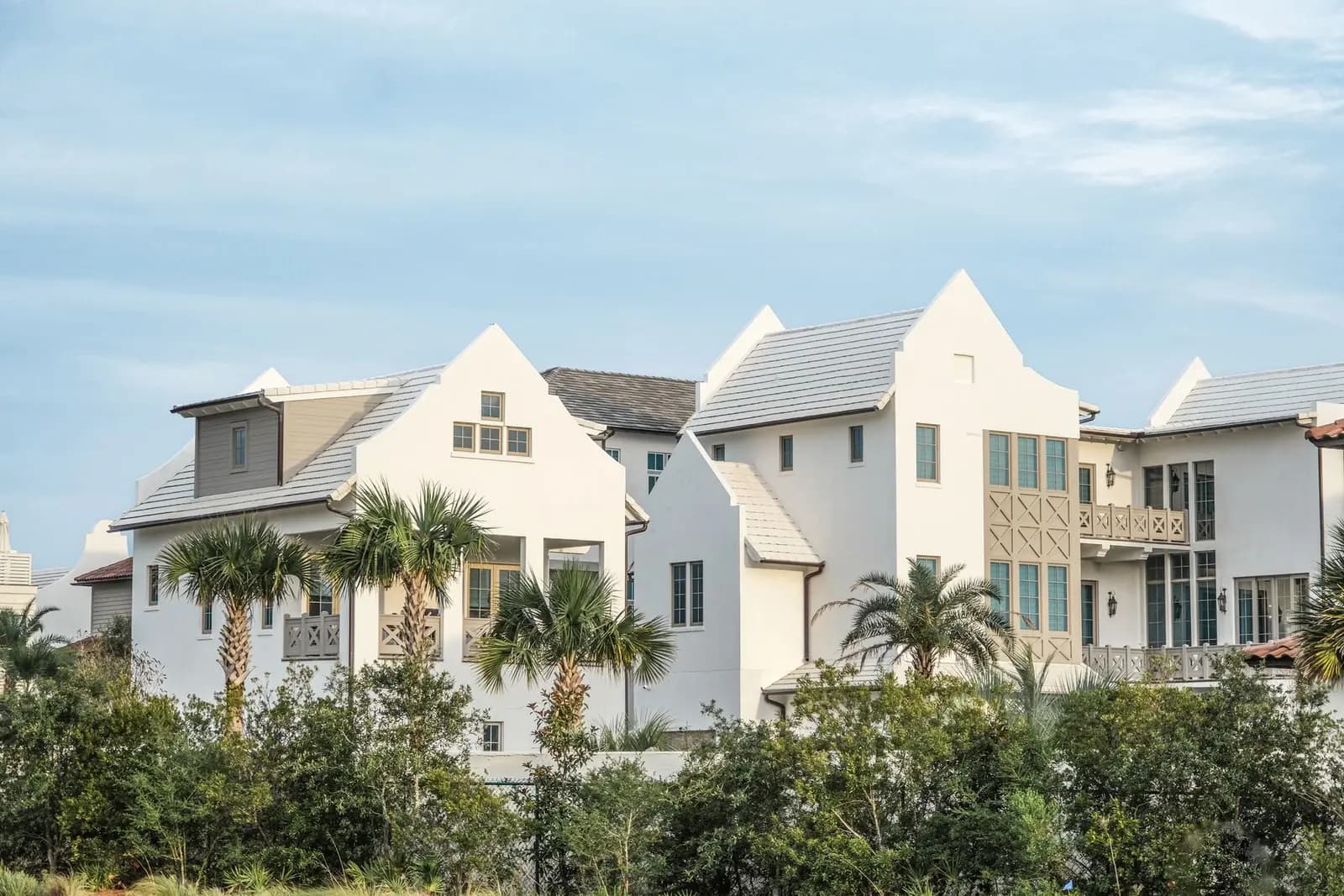 White houses and palm trees in a coastal neighborhood. Real estate marketing that replies without steering